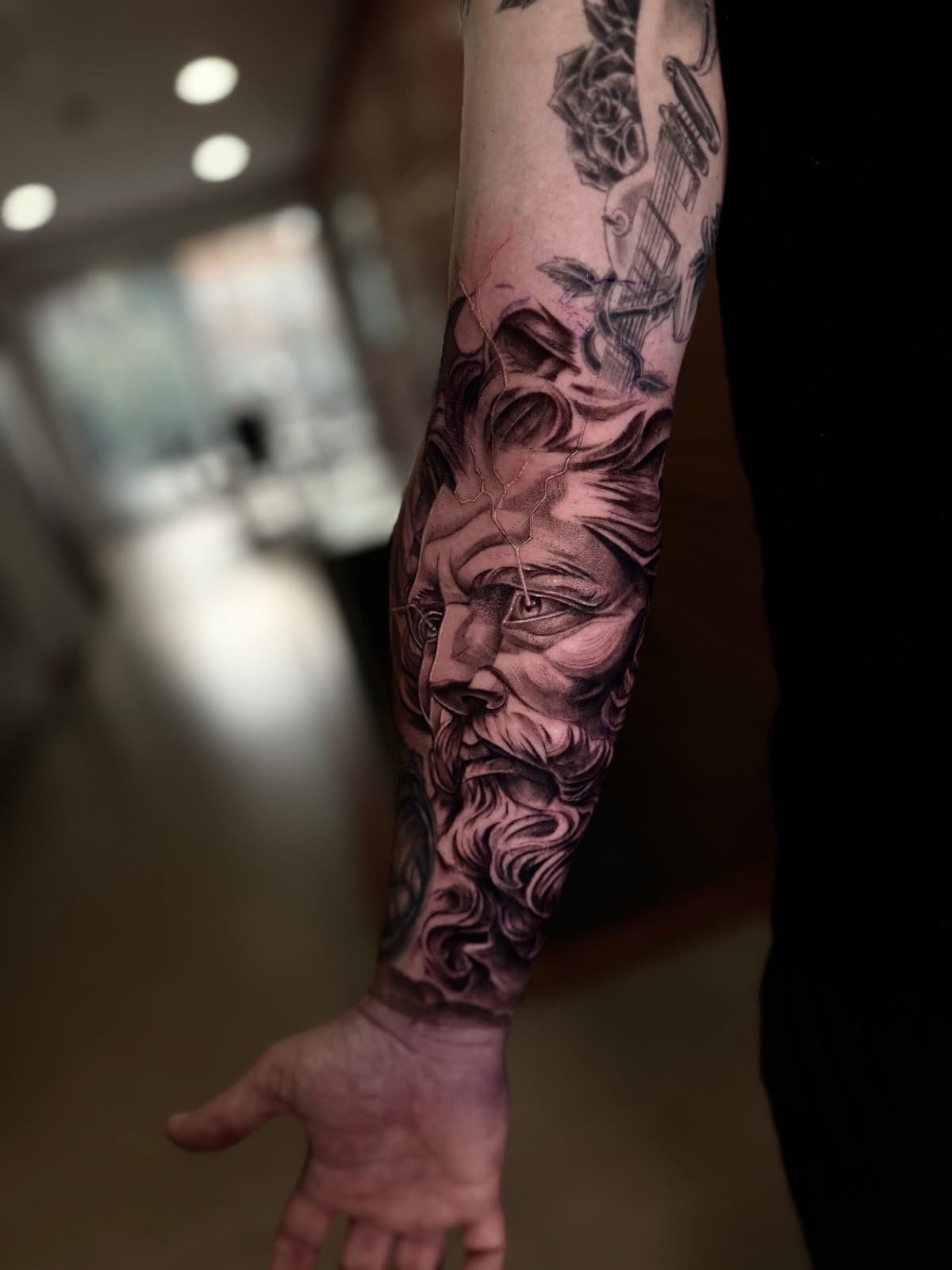 Black and grey Greek god portrait forearm tattoo by Tobias Meredith in Melbourne