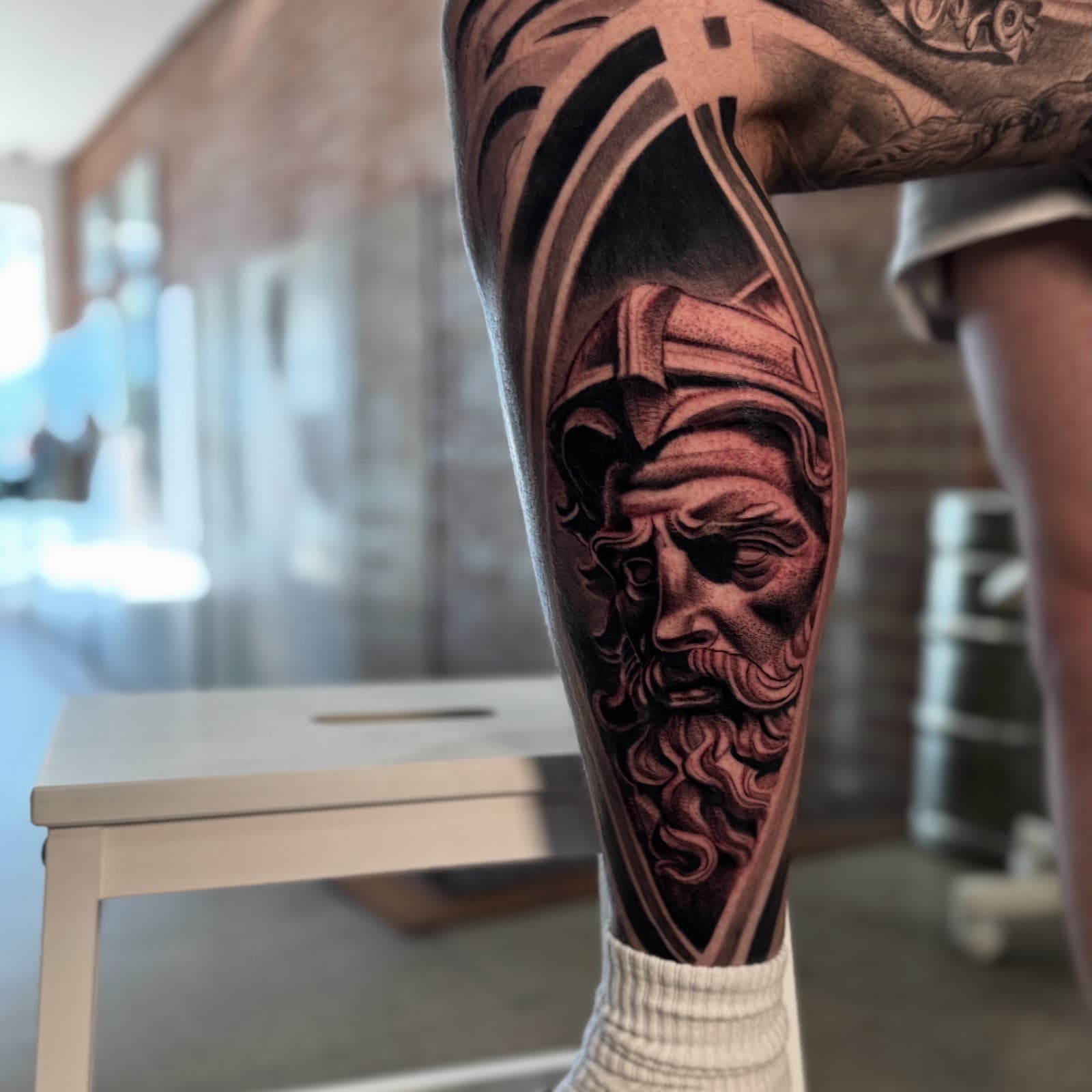 Poseidon-style black and grey portrait calf tattoo by Tobias Meredith