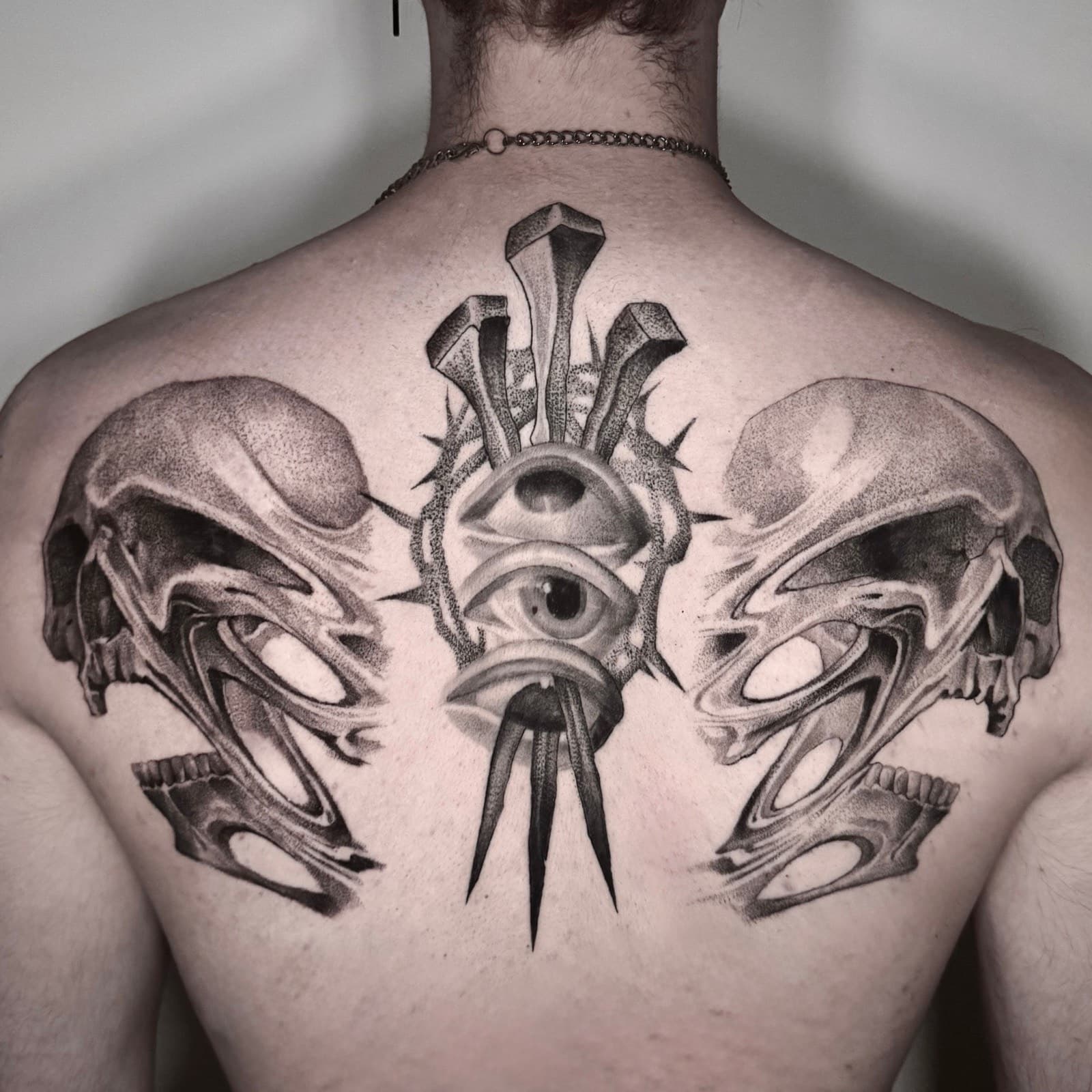 Surreal black and grey back piece with eyes and skulls by Tobias Meredith